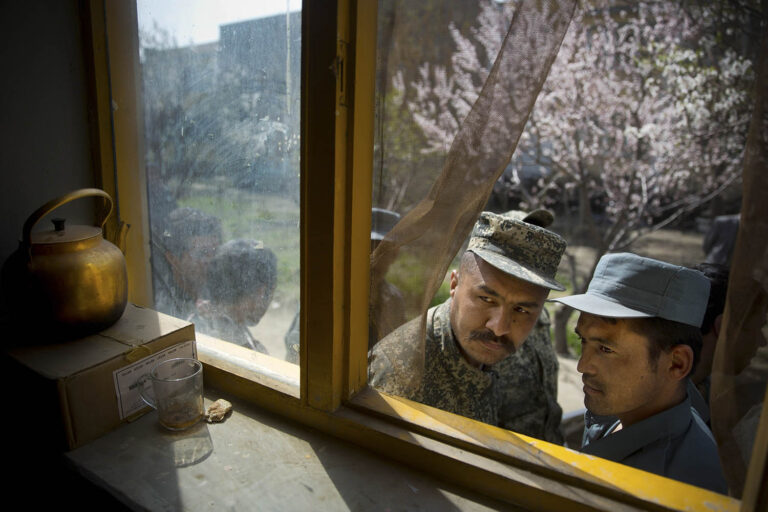 חייל אפגני (משמאל) ושוטר מציצים מחלון ליד בית ספר בקאבול, בזמן שהם ממתינים לקבל את כרטיס הבוחר שלהם ביום האחרון להרשמה לבחירות לנשיאות, 1 באפריל 2014. (AP Photo/Anja Niedringhaus)