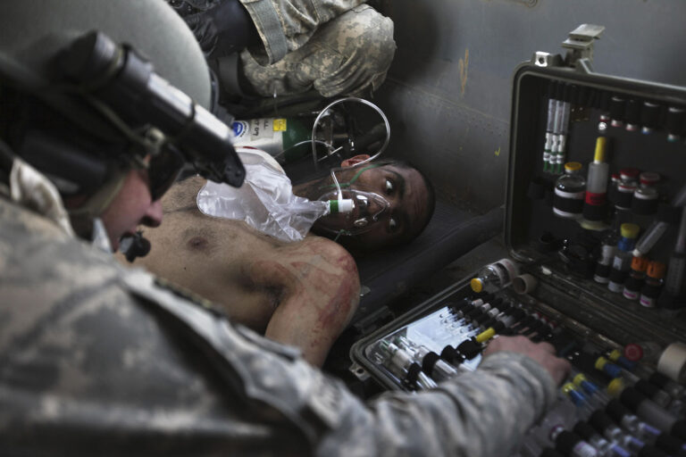 החובש המוטס רוברט ב' קודרי מעניק טיפול רפואי לחייל בצבא הלאומי האפגני שנפגע מירי, במהלך משימת פינוי מוסק במרג'ה שבמחוז הלמנד, 17 בפברואר 2010 (AP Photo/Brennan Linsley)