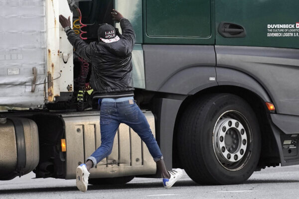מהגר מנסה לקפוץ על משאית בקאלה, צרפת. אם המשאית שעלה עליה לא נוסעת לבריטניה, הוא קופץ ממנה ומתחיל הכול מחדש (AP Photo/Christophe Ena)