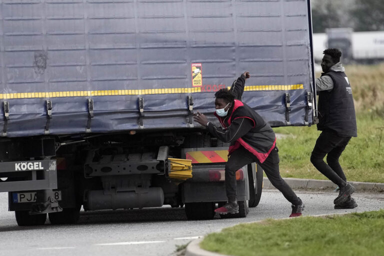 שני מהגרים מנסים לקפוץ על משאית. 18 אלף מהגרים התגלו על משאיות ב-2020, ו-11 אלף נוספים עד כה ב-2021 (AP Photo/Christophe Ena)