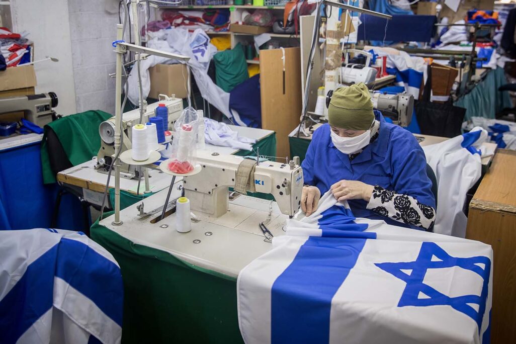 A worker sewing  Israeli flags at the Berman's Flags and Embroidery factory in Jerusalem. Worker pictured is not connected to article. (Photo: Yonatan Sindel / Flash90)