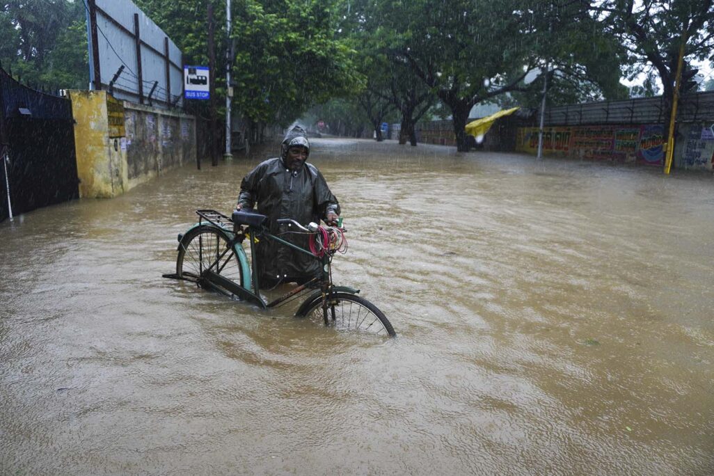 גבר הולך עם אופניים ברחוב שהוצף בשיטפון בדרום מזרח הודו  (AP Photo/R. Parthibhan)