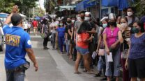 תושבי הפיליפינים בתור לחיסון קורונה מחוץ לבית ספר, ביום הראשון של מבצע חיסונים רחב במדינה, 29 בנובמבר 2021 (AP Photo/Aaron Favila)