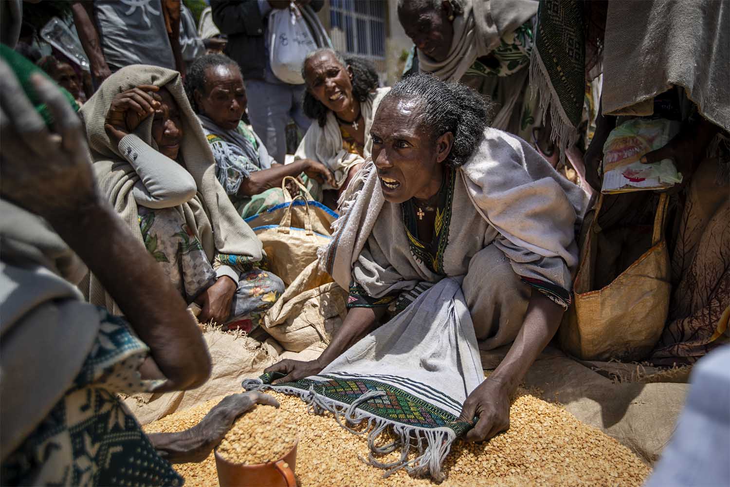 תושבת חבל תיגראי בצפון אתיופיה נאבקת על הקצאת אפונה צהובה שחולקה על ידי ארגון סיוע בעיירה אגולה, מלחמת האזרחים המתמשכת במדינה יצרה משבר הומניטרי. 8 במאי 2021 (צילום: AP Photo/Ben Curtis)