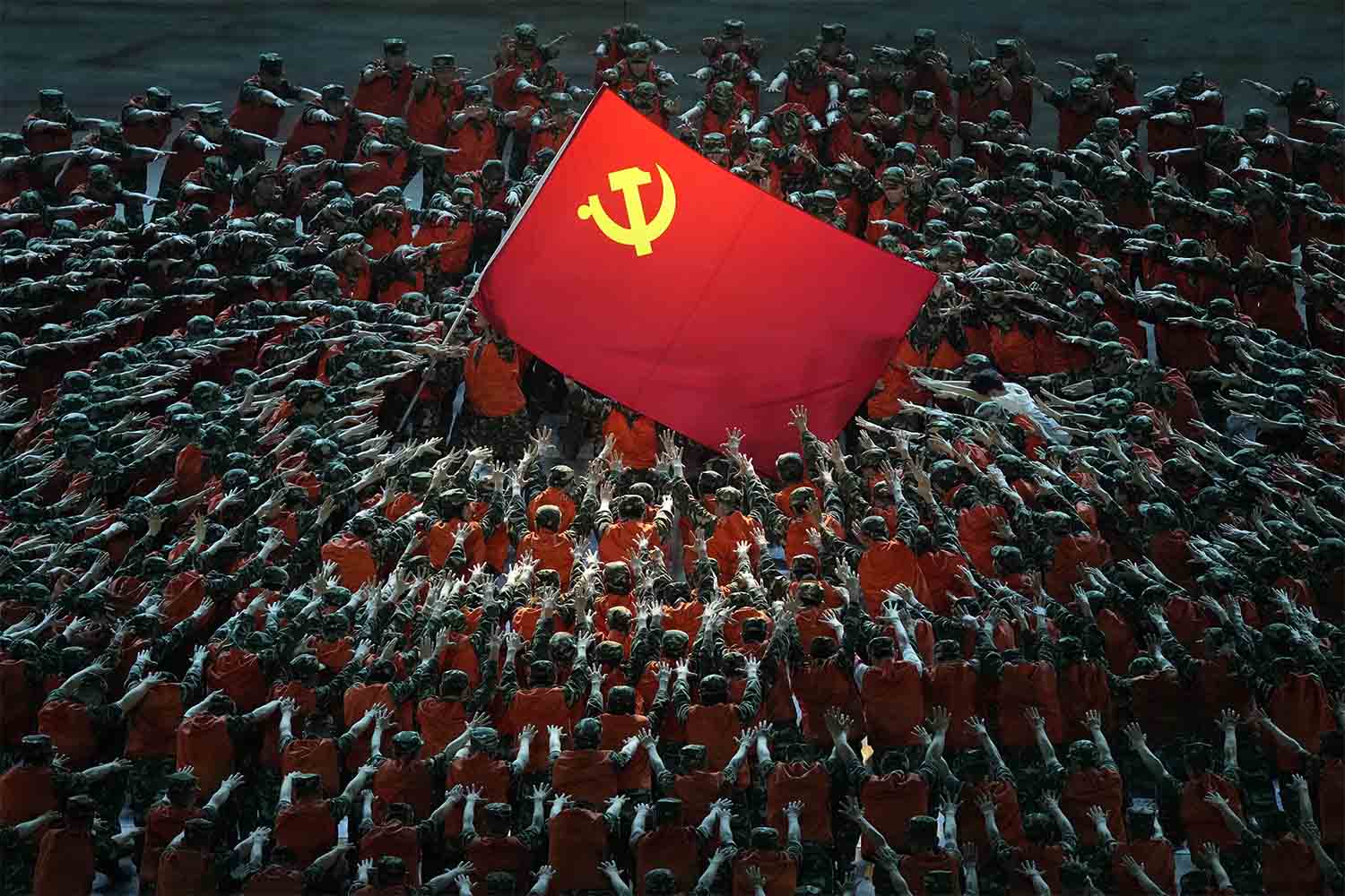 שחקנים הלבושים כעובדי הצלה מתאספים סביב דגל המפלגה הקומוניסטית במהלך מופע חגיגי לקראת יום השנה ה-100 להקמת המפלגה הקומוניסטית הסינית בבייג'ינג. 28 ביוני 2021 (צילום: AP Photo/Ng Han Guan)