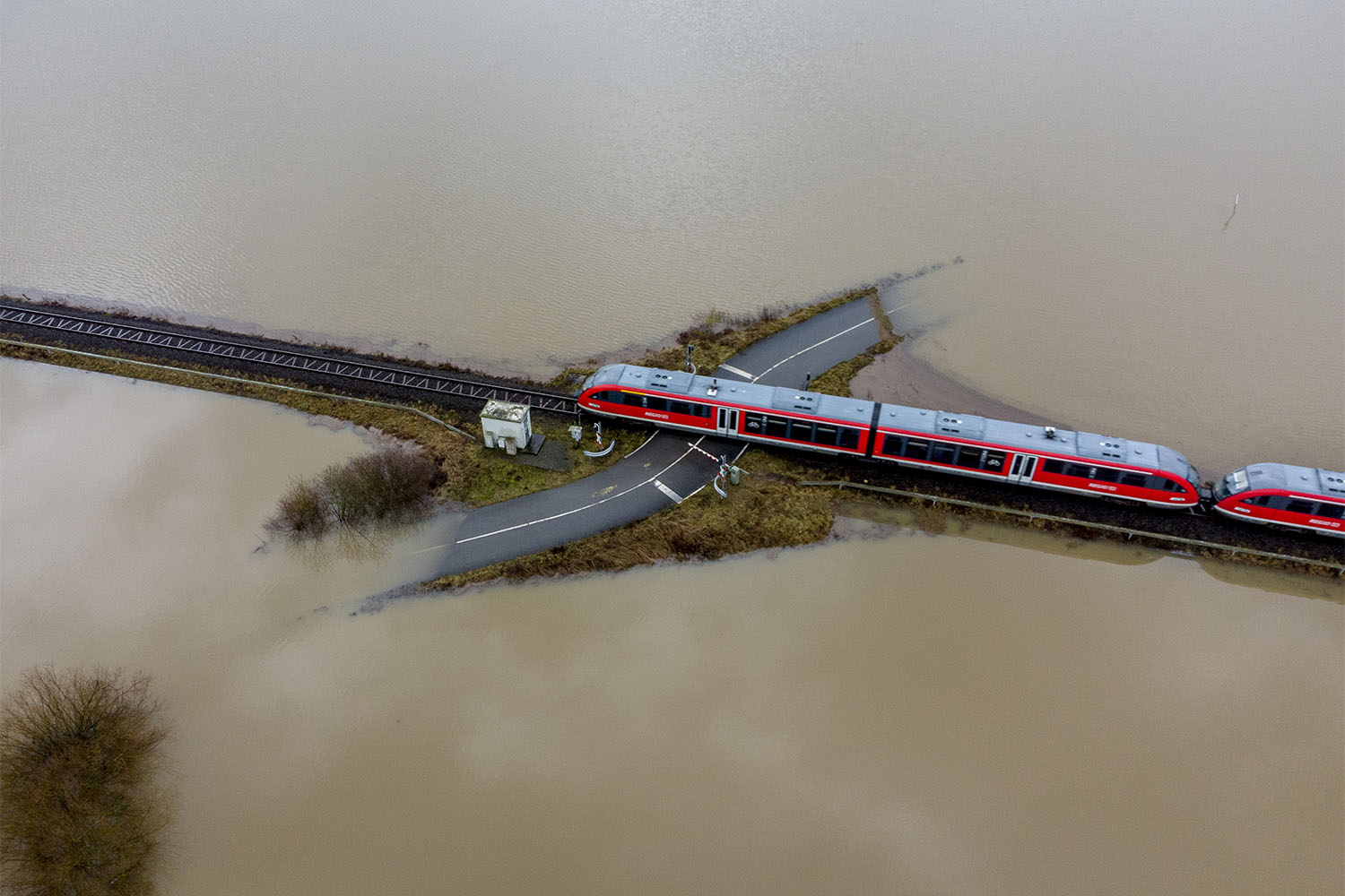 רכבת חולפת במעבר מסילה מוקף במי שיטפונות מגשם ושלג נמס ליד פרנקפורט, גרמניה. ההתחממות הגלובלית הגיעה השנה לאירופה. 3 בפברואר 2021 (צילום: AP Photo/Michael Probst)