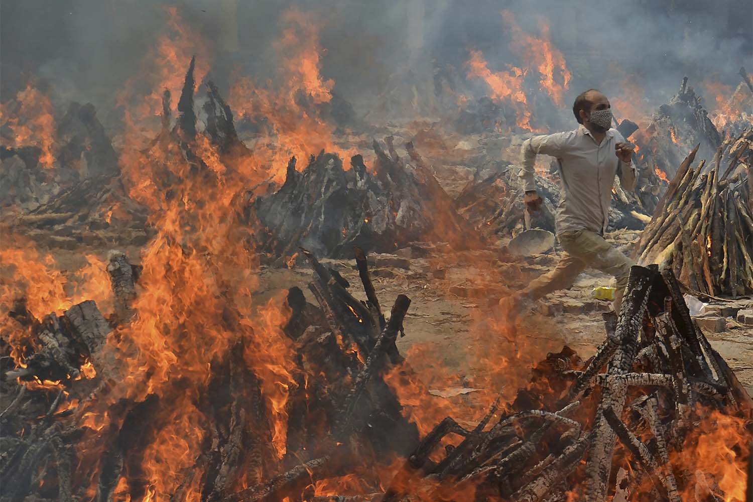 אדם נמלט מהחום של שריפת גופותיהם של נפטרי קורונה בפאתי ניו דלהי, הודו  (צילום: AP Photo/Amit Sharma)