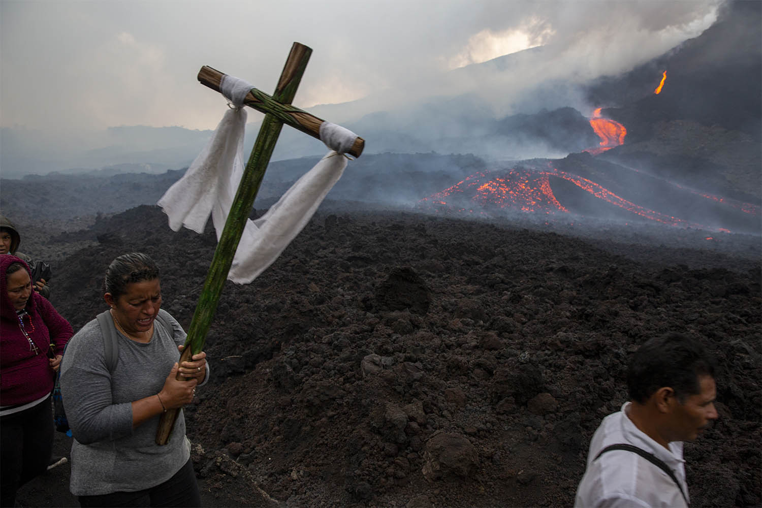 אישה נושאת צלב במהלך עלייה לרגל לתפילה להפסקת פעילותו של הר הגעש פאקאיה, בסן ויסנטה פאקאיה, גואטמלה. הר הגעש, 50 קילומטרים מדרום לבירת גואטמלה, הפך לפעיל בתחילת השנה. 5 במאי 2021 (צילום: AP Photo/Moises Castillo)