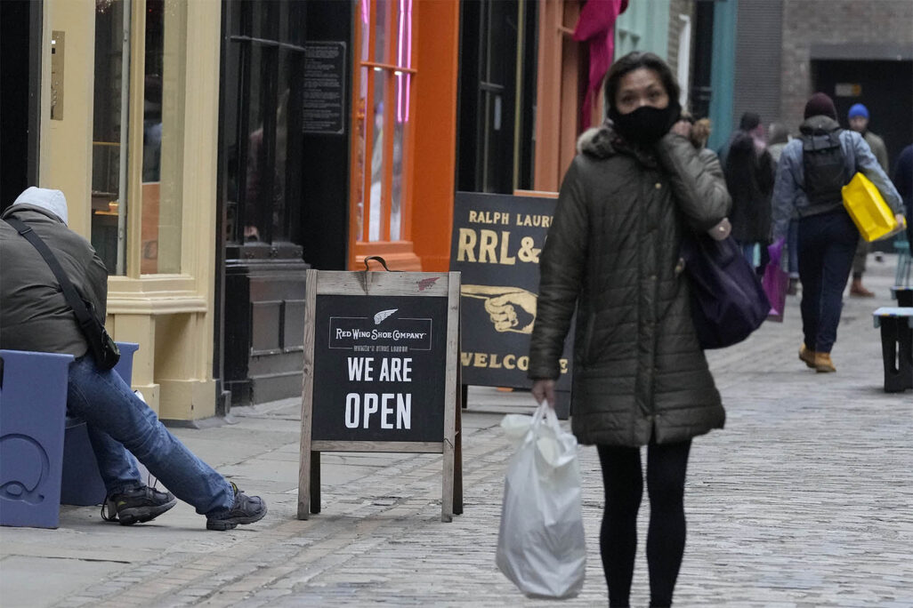 מספר קטן של קונים ברחוב בלונדון עוברים ליד שלט עליו כתוב "אנחנו פתוחים" (צילום: AP Photo/Frank Augstein)