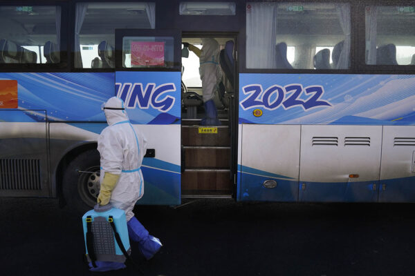 עובדים בבגדי מגן מחטאים אוטובוס שישרת את המשתתפים באולימפיאדת החורף בבייג'ינג (צילום אילוסטרציה: AP Photo/Jae C. Hong)