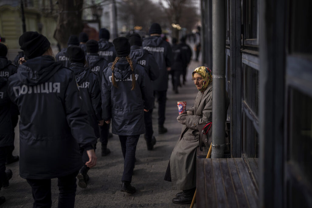 שוטרים אוקראינים חולפים על פניה של אשה מבוגרת לפני הפלישה הרוסית למדינה (צילום: AP Photo/Emilio Morenatti)