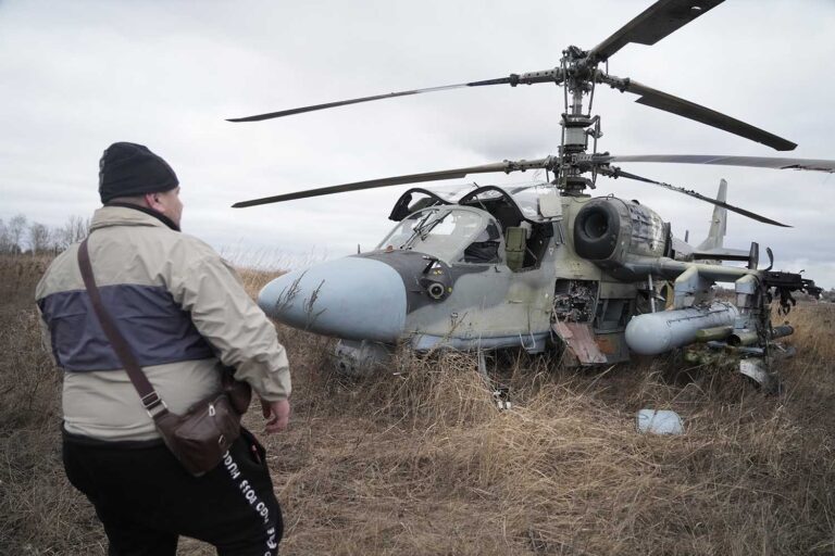A man standing in front of a Russian Ka-52 helicopter gunship is seen in the field after a forced landing outside Kyiv, Ukraine, Thursday, Feb. 24, 2022. (Photo: AP Photo/Efrem Lukatsky)