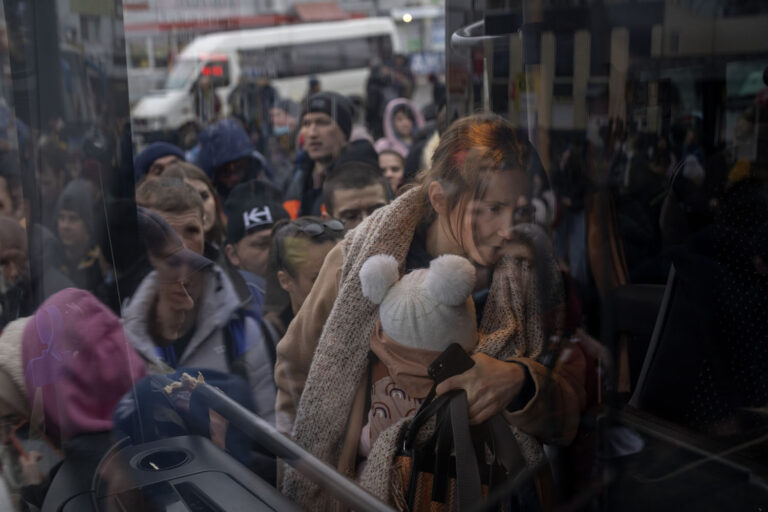 A woman holds her baby as she gets on a bus leaving Kyiv, Ukraine, Thursday, Feb. 24, 2022. (Photo: AP Photo/Emilio Morenatti)