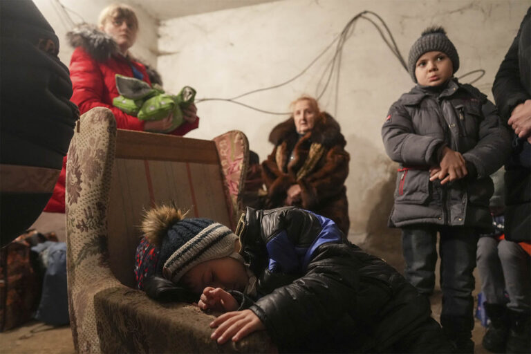 A child sleeps in an armchair as others stand around in a shelter during Russian shelling, in Mariupol, Ukraine, Thursday, Feb. 24, 2022. (Photo: AP Photo/Evgeniy Maloletka)