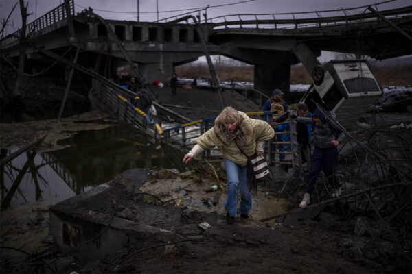 אישה נמלטת מהפצצות רוסיות בפאתי העיר קייב (AP Photo/Emilio Morenatti)