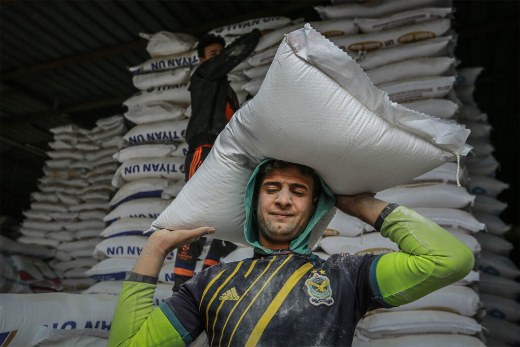 עובד בשוק בעיראק פורק שקי קמח, 9 במרץ 2022 (צילום אילוסטרציה: Ameer Al Mohammedaw/picture alliance via Getty Images)