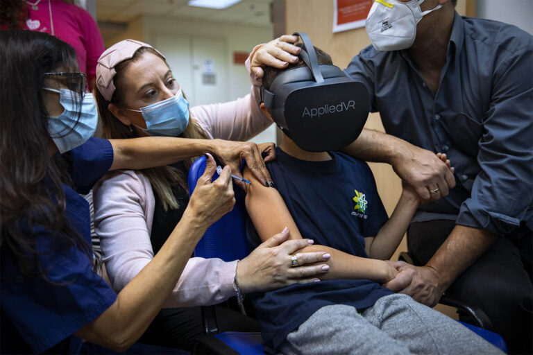 רמת גן, ישראל. רפאל פלד, בן 8, מרכיב משקפי מציאות מדומה כשהוא מתחסן בבית החולים שיבא תל השומר, 22 בנובמבר 2021 (צילום: AP Photo/Oded Balilty)