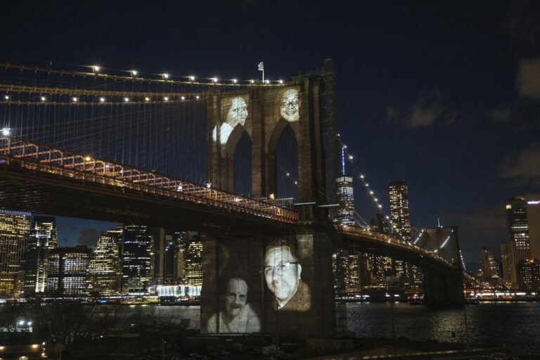 ניו יורק, ארצות הברית. תמונותיהם של תושבי העיר שמתו מקורונה מוקרנות על גשר ברוקלין, 14 במרץ 2021 (צילום: AP Photo/Kevin Hagen)