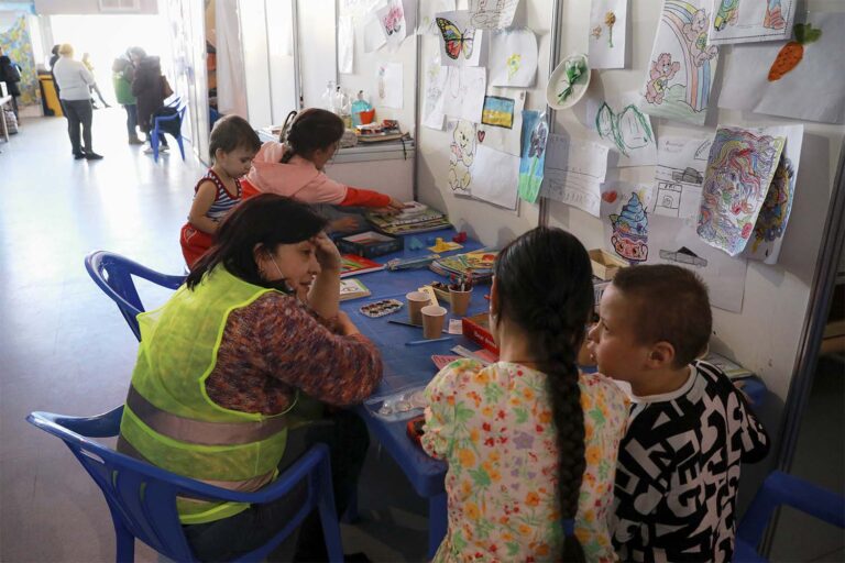 מתנדב משוחח עם ילדים שברחו מהמלחמה באוקראינה עם משפחותיהם במרכז לאירוח פליטים בקישינב, מולדובה (צילום: AP Photo/Aurel Obreja)