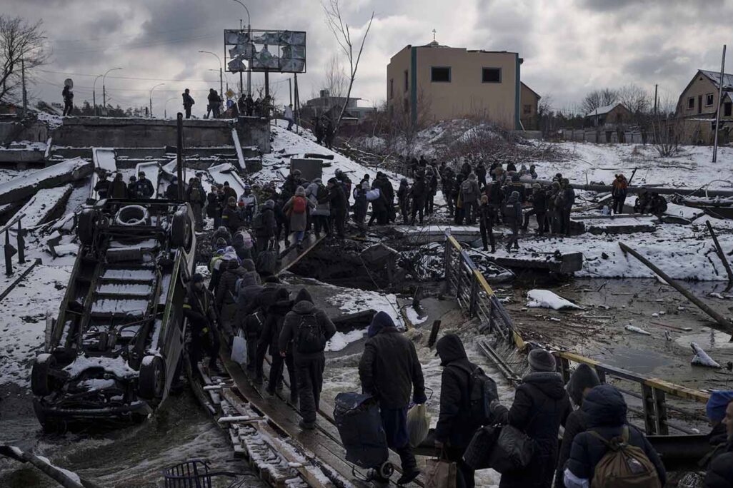 Ukrainians cross an improvised path under a destroyed bridge while fleeing Irpin, in the outskirts of Kyiv, Ukraine. (Photo: Felipe Dana/AP Photo)
