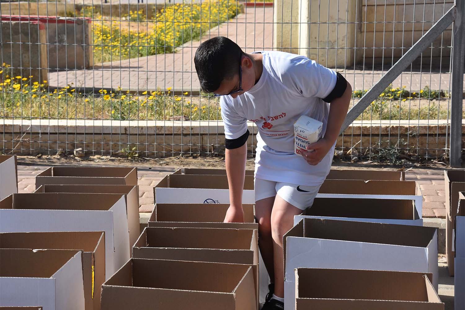 מתנדב צעיר ממלא ארגזי מזון במסגרת פעילות עמותת ״להשביע את הלב״ (צילום: הדס יום טוב)