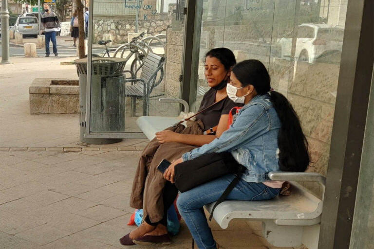 נשים ממתינות בתחנת אוטובוס ביום שלאחר ביטול חובת עטיית המסכות בישראל (צילום: אור גואטה)