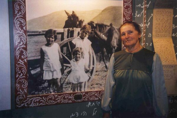 תמה בבית שטורמן על רקע התמונה שלה עם אחיה משה ודבורה. תמה הקטנה מלפנים (צילום: אלבום פרטי)