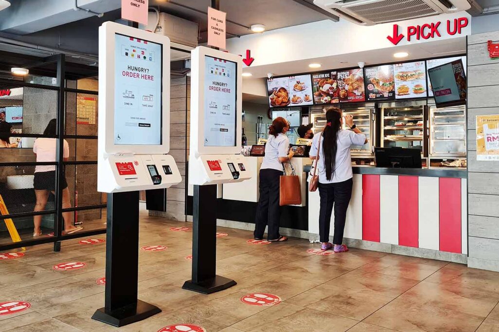 Self-order kiosk machines installed inside of a KFC fast food restaurant. (Photo: kaykhoon / Shutterstock)