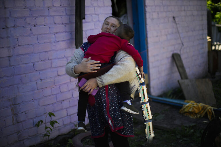 אישה וילד יוצאים מבית שהופגז בהתקפה רוסית במזרח אוקראינה (צילום: AP Photo/Francisco Seco)