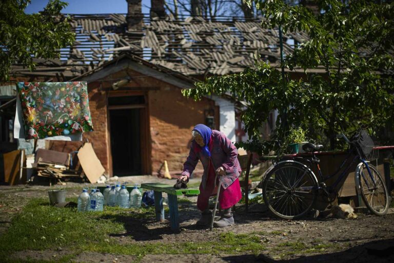 אישה מבוגרת חוזרת אל ביתה שהופגז בפוקרובסק במזרח אוקראינה (צילום: AP Photo/Francisco Seco)