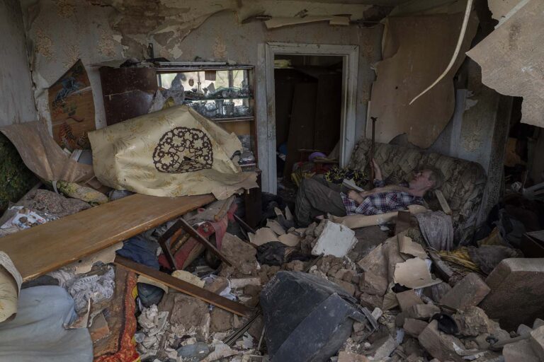 אדם יושב על ספה בין הריסות ביתו שנהרס מפגיעת טילים רוסיים בדרוז'קובקה שבמזרח אוקראינה (AP Photo/Bernat Armangue)