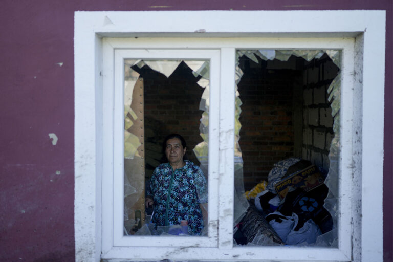 אשה שביתה נהרס בהפצצות הרוסיות מצטלמת במקום בו גרה עם עוד 18 בני משפחתה בפאתי קייב הבירה (AP Photo/Natacha Pisarenko)