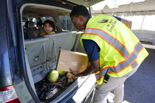 מתנדב ממלא רכב בחבילות מזון בבנק המזון של סיינט מארי בפניקס, אריזונה. שווי חבילה הוא 75 דולר, והיא ניתנת למאות משפחות מדי יום (AP Photo/Ross D. Franklin)