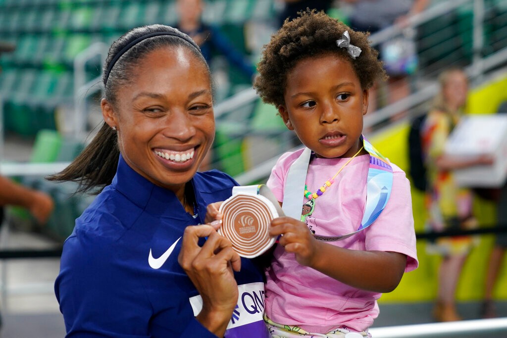 אליסון פליקס מעניקה לבתה את המדליה האחרונה בקריירה המפוארת שלה, לאחר גמר השליחים המעורב 4x400 מטר באליפות העולם באתלטיקה (צילום: AP / Charlie Riddle)