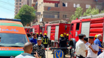 כוחות חירום והצלה מצריים מרחיקים אזרחים מאזור השריפה, ברקע צוותי כבאים נערכים לכיבוי השריפה (צילום: AP Photo/Mohamed Salah)