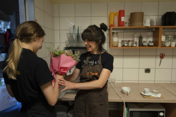 טטיאנה ביילוס, מימין, מעניקה לחברתה לעבודה, גם היא פליטה מאוקראינה, פרחים לכבוד יום הולדתה, במקום עבודתן בפולין (צילום: AP Photo/Michal Dyjuk)