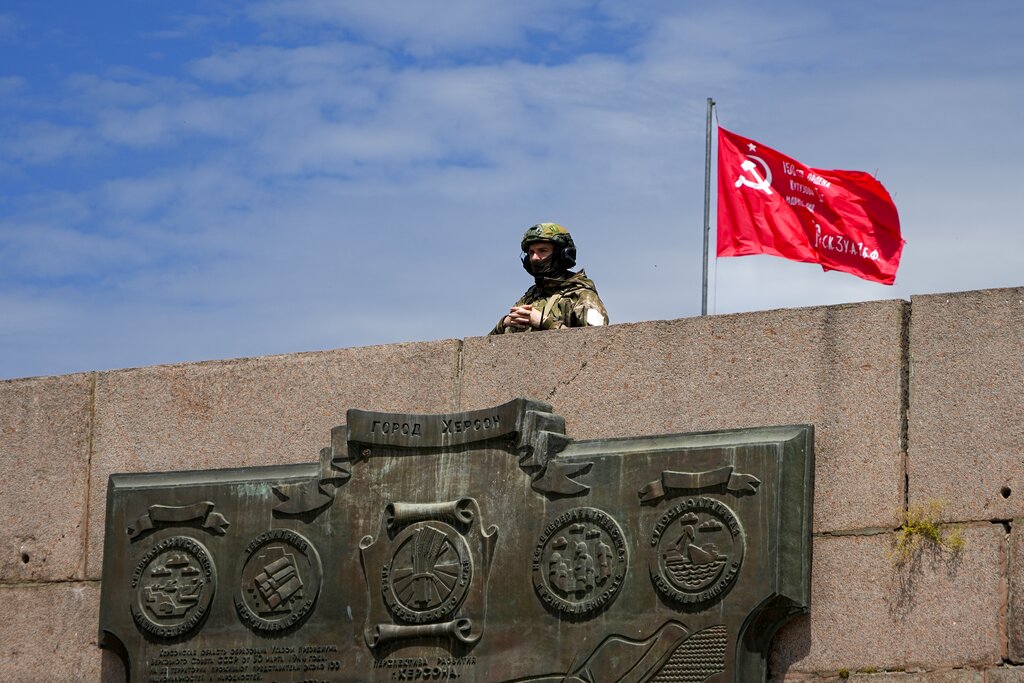 חייל רוסי שומר על בניין בשליטת הצבא הרוסי, עם העתק של דגל מתקופת הניצחון הרוסי על הנאצים (צילום: AP Photo)