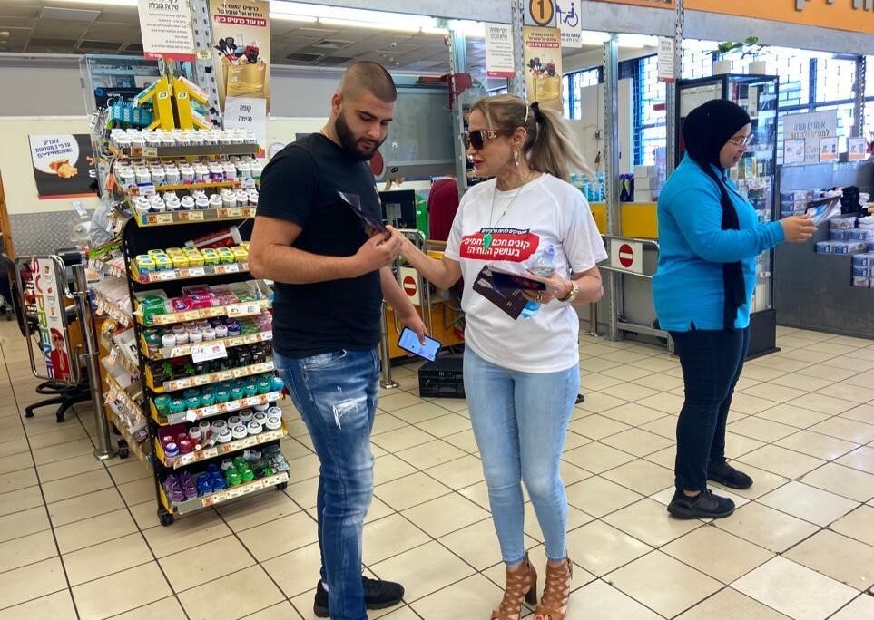 An activist encourages shoppers to boycott products distributed by importers who have attempted to raise prices (Photo: Histadrut and HaNoar HaOved veHalomed)