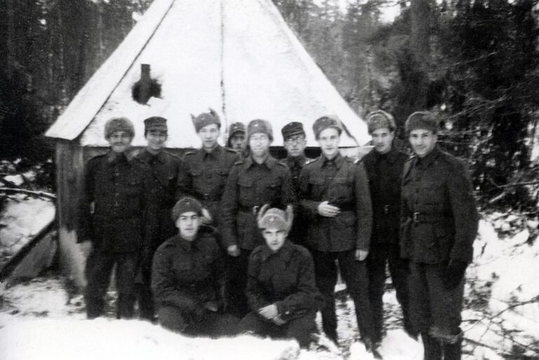 אבנר צבי (עומד, במרכז) עם קבוצת חיילים יהודים בצבא הפיני במלחמת ההמשך, על רקע אוהל התפילה שהוקם עבורם, סמוך לנהר הסביר שבמחוז לנינגרד (צילום: ויקימדיה)