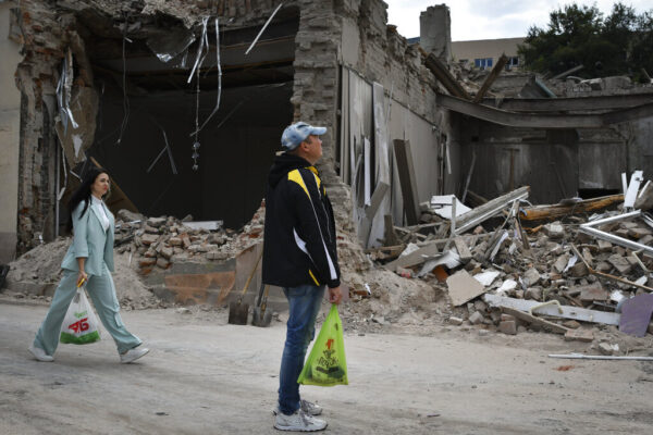 אזרחים אוקראינים חולפים על פני בניין שהופצץ בעיר דנייפרו (צילום: AP Photo/Andriy Andriyenko)