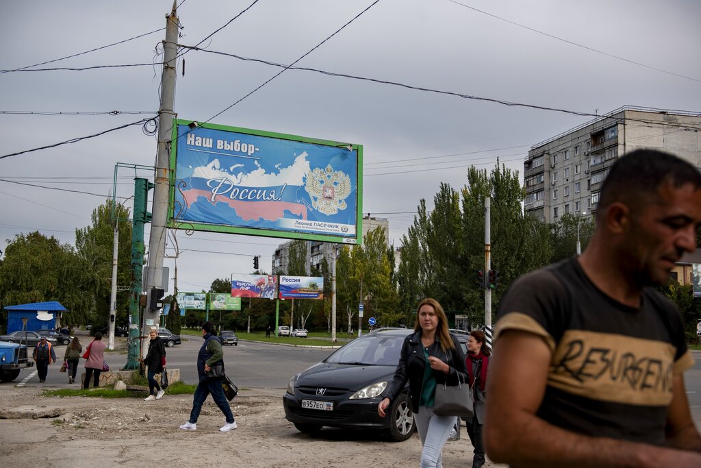 אנשים ברחוב בלוהנסק, הנשלטת על ידי בדלנים הנתמכים על ידי רוסיה. ברקע שלטים על הקוראים למשאל עם על הצטרפות לרוסיה (צילום: AP)