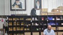 לוי שניאורסון אורז חבילות שי לראש השנה, מעליו תמונת הרבי מלובביץ' (צילום: מאיה רונן)