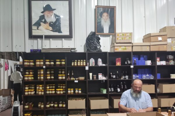 לוי שניאורסון אורז חבילות שי לראש השנה, מעליו תמונת הרבי מלובביץ' (צילום: מאיה רונן)