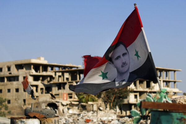 דגל סוריה עם תמונה של הנשיא בשאר אל-אסד במתקן צבאי ליד דמשק (צילום: AP/Hassan Amr)
