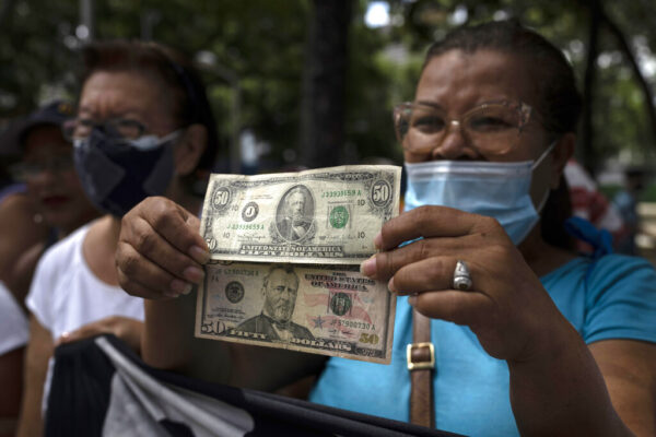 מפגינה אוחזת שטרות של דולר בקרקס, ונצואלה (AP Photo/Ariana Cubillos, File)