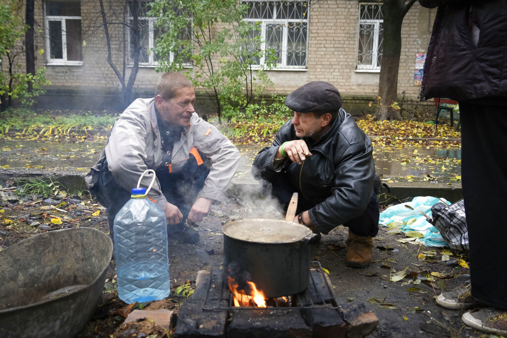 תושבי העיר בחמוט מבשלים מזון על מדורה מחוץ לביתם, על רקע התגברות ההפצצות של כוחות רוסים על העיר, 26 באוקטובר 2022 (AP Photo/Efrem Lukatsky)