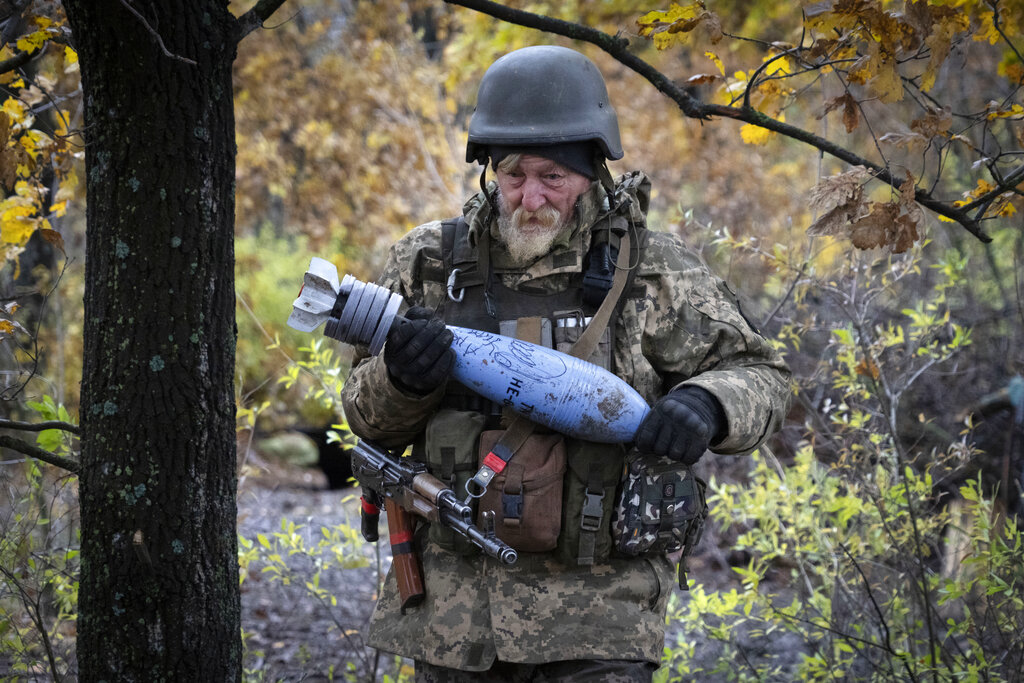 חייל אוקראיני אוחז בפצצה עם מסר לצבא הרוסי בפאתי העיר בחמוט, 27 באוקטובר 2022 (AP Photo/Efrem Lukatsky)