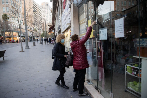 אישה נועלת את החנות שלה בירושלים (צילום: יונתן זינדל/פלאש90)