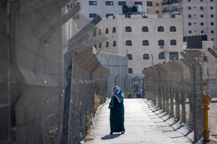امرأة فلسطينيّة بالقرب من الجدار الفاصل بين مخيم شعفاط وحي بسجات زئيف، 9 تشرين أول/أكتوبر 2022، بعد يوم واحد من عملية الهجوم على الحاجز القريب من المخيم (تصوير: يونتان سيندال/ فلاش 90)