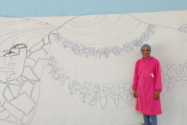 שירין מחאג'נה על רקע ציור הקיר שיצא אדהם ג'בארין, אותו יצבעו באי הפסטיבל (צילום: יניב שרון)